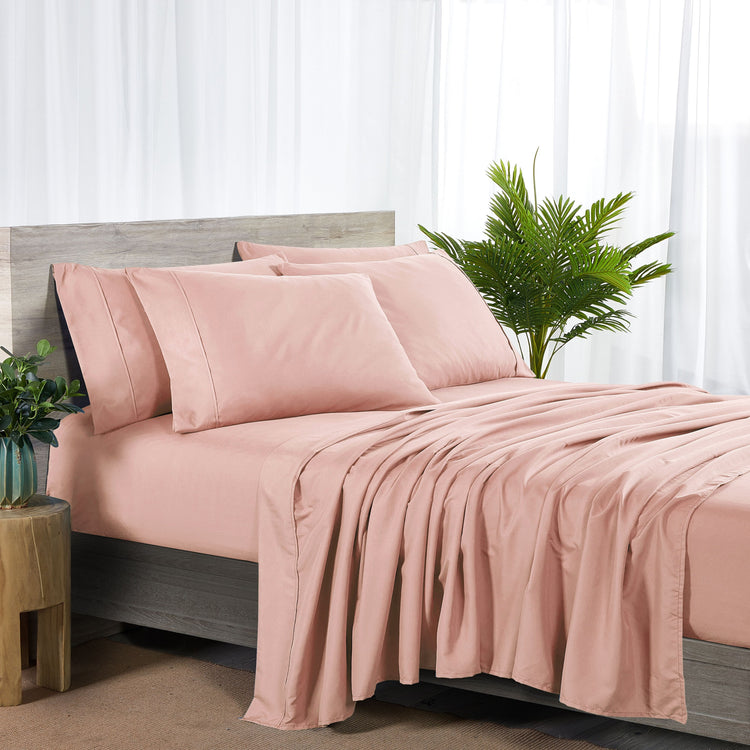 Pink bedding set on a bed with a plant in the background