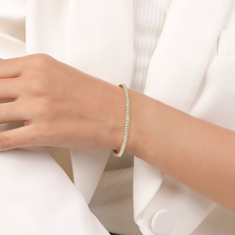 Gold bracelet on a person's wrist with a white background