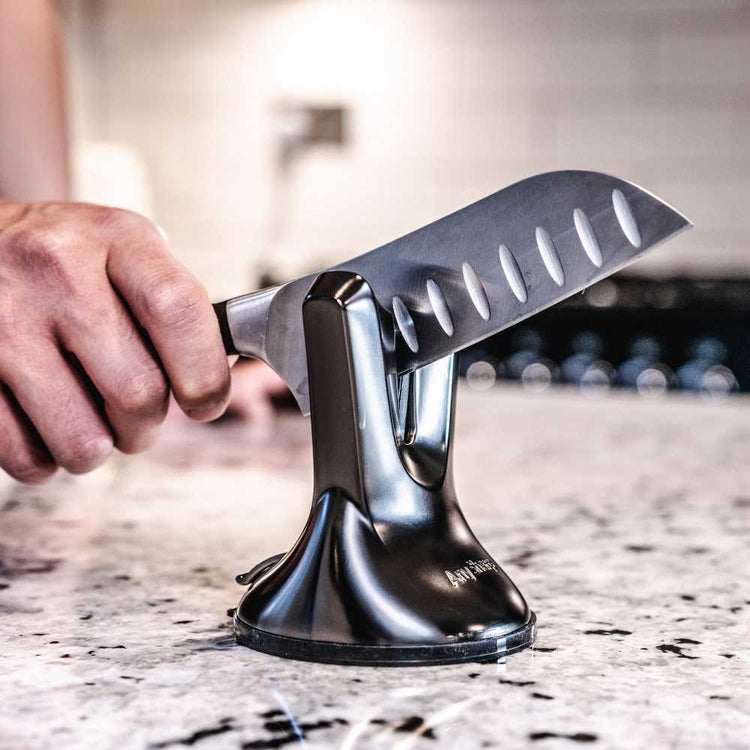 Person using a knife sharpener on a kitchen counter