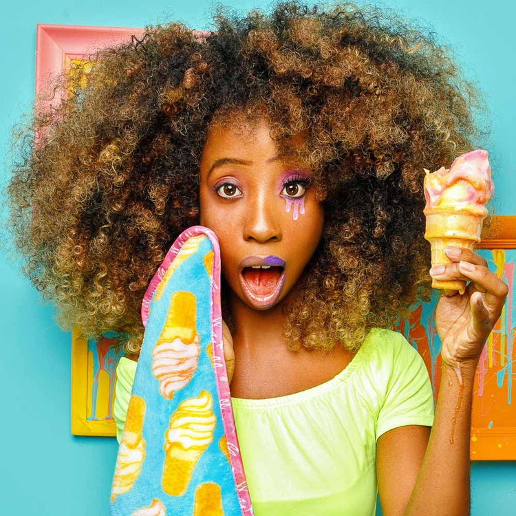 Woman with afro holding a colorful ice cream cone and towel against a blue background