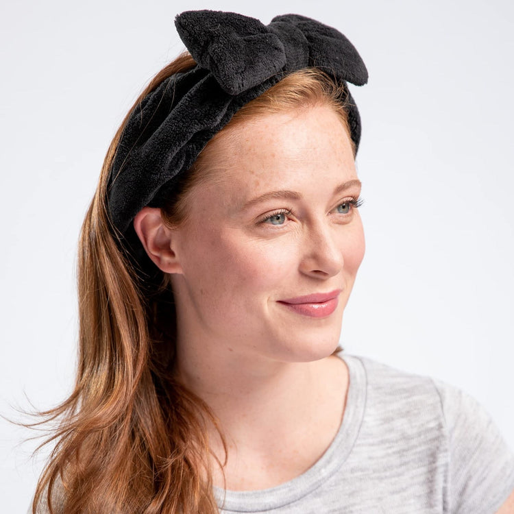 Woman wearing a black headband with a bow on a white background