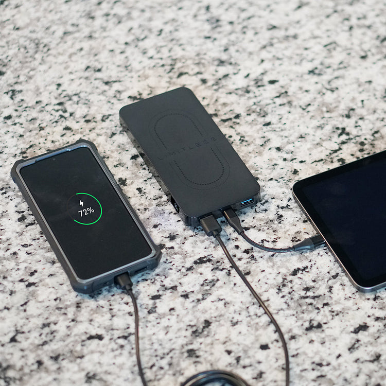 Black portable power bank with two devices charging on a speckled countertop