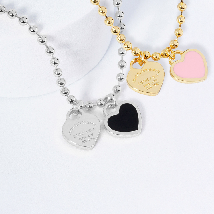 Two heart-shaped pendant necklaces on a white background