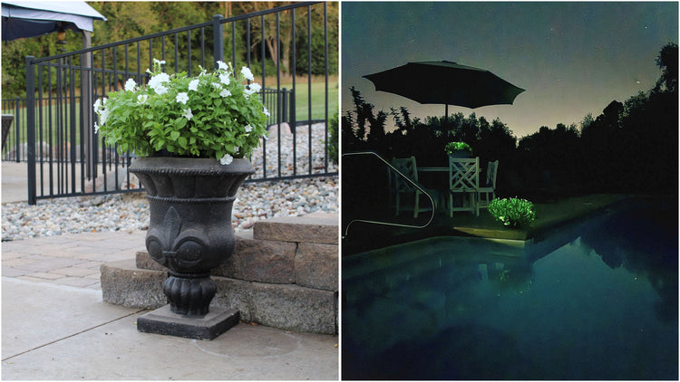 Black urn with greenery on a patio next to a pool area at night.