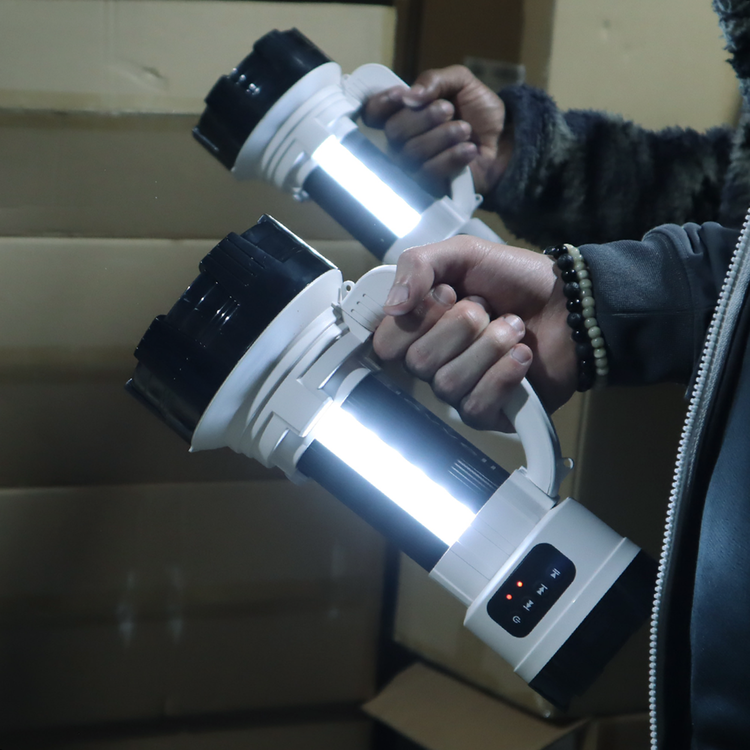 Person holding a white and black flashlight with a cardboard box in the background