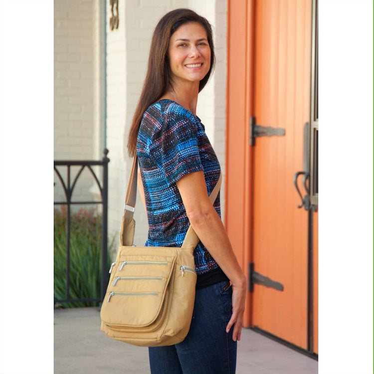 A brown crossbody vegan leather daybag with multiple zippered compartments and an adjustable shoulder strap.