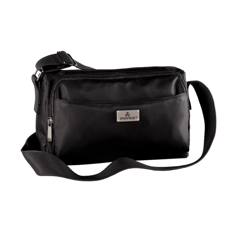 A person seated on a bench with a striped skirt and a black top, wearing a blue crossbody bag with multiple compartments.