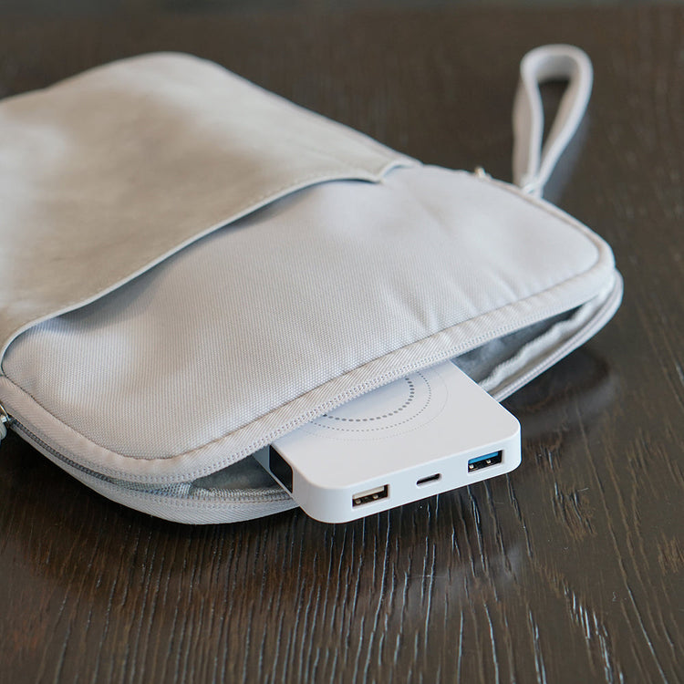 Portable USB hub attached to a beige carrying case on a wooden surface
