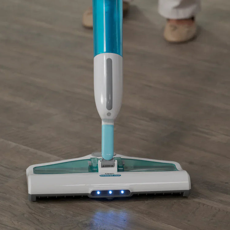 Mopping device on a wooden floor with a person's feet in the background