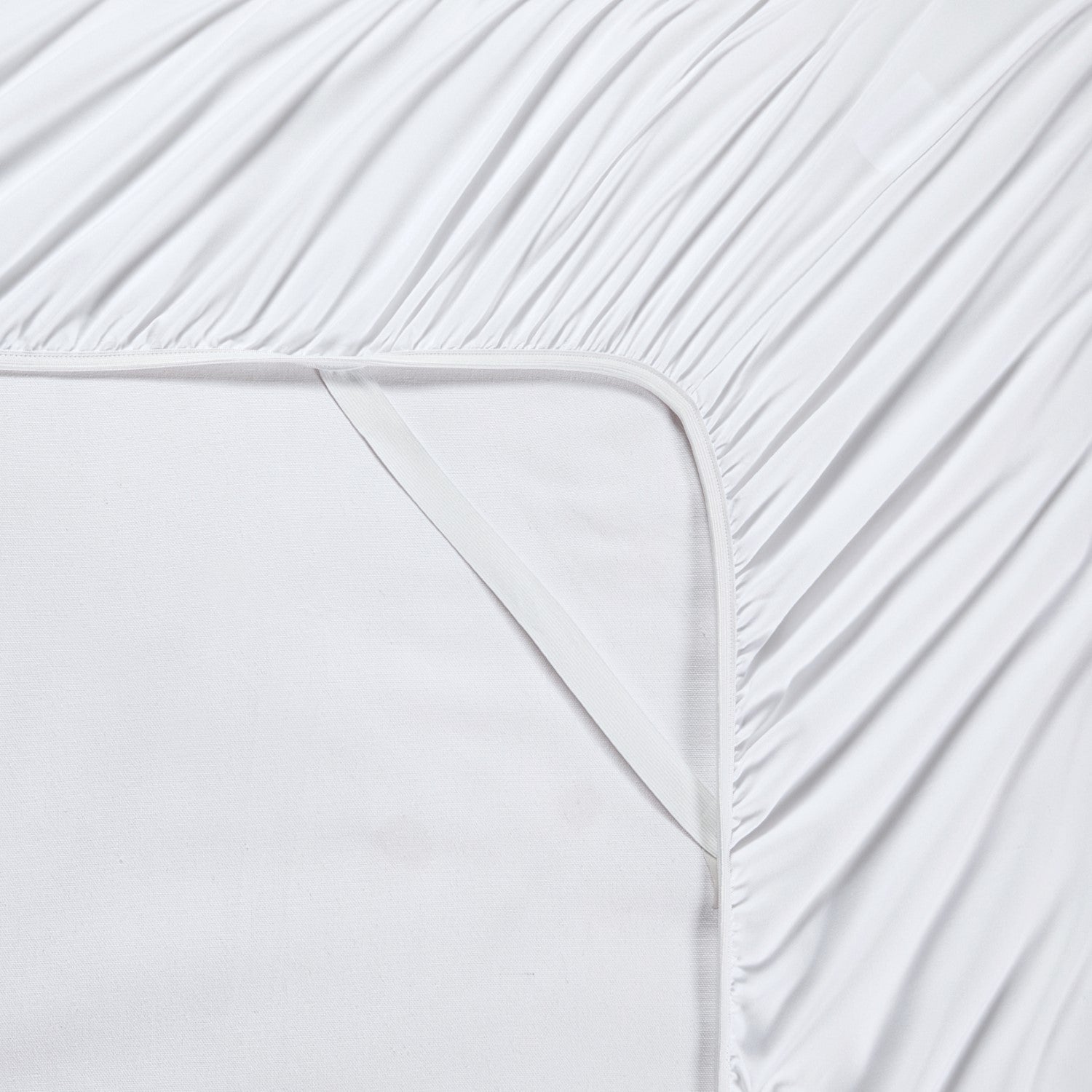 Close-up of white fitted sheet with subtle texture on a bed.