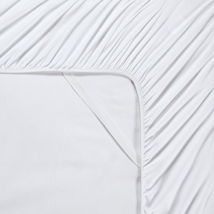 Close-up of white fitted sheet with subtle texture on a bed.