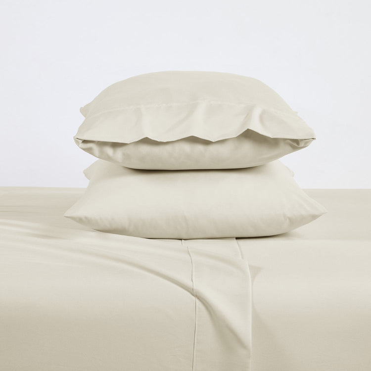 Beige pillows and bed sheets on a light gray background