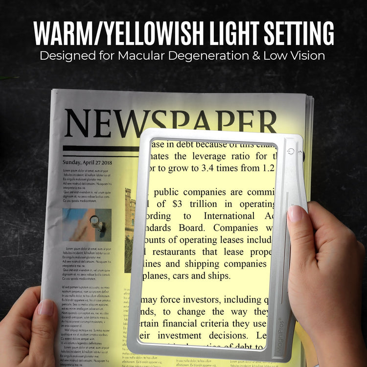 Hand holding a magnifying device over a newspaper with text, set against a dark background.