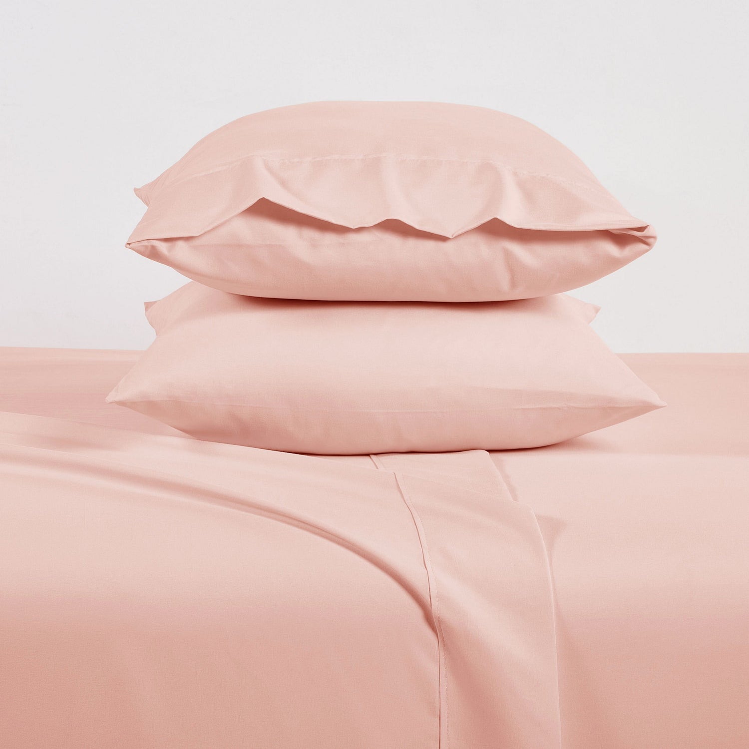 Pink bedding set with two pillows on a light pink background
