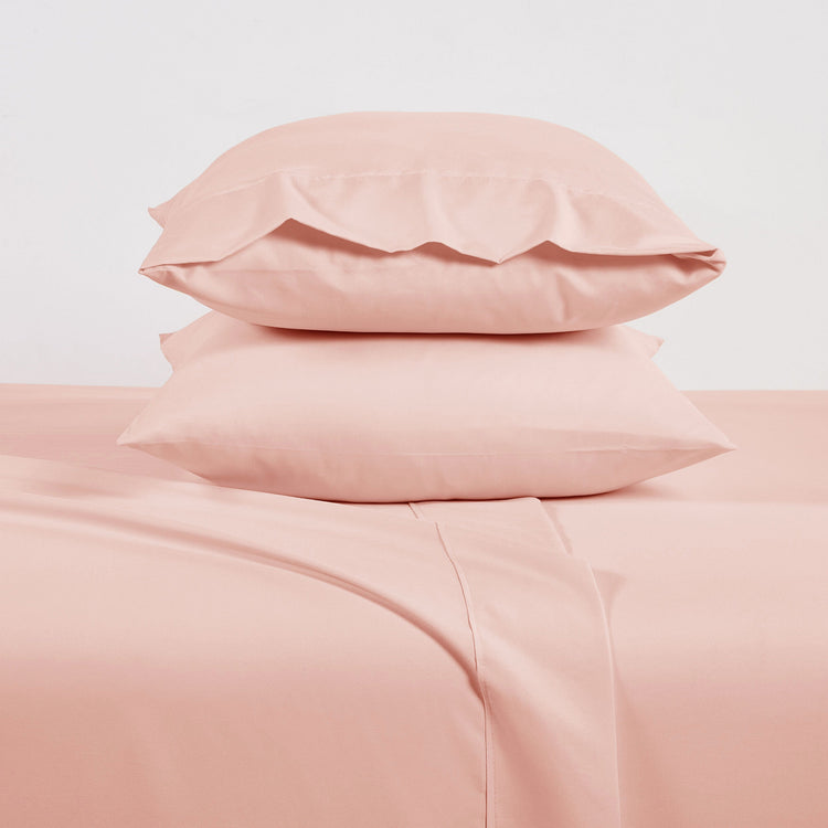 Pink bedding set with two pillows on a light pink background