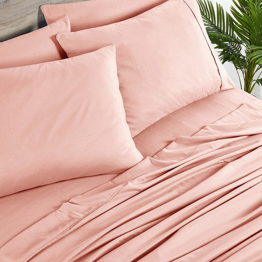 Pink bedding set on a bed with matching pillows in a bedroom setting.