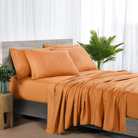Orange bedding set on a bed with matching pillows in a bedroom setting.