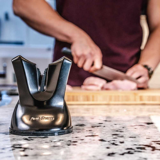 A black, professional knife sharpener with a suction cup base and a metallic blade.