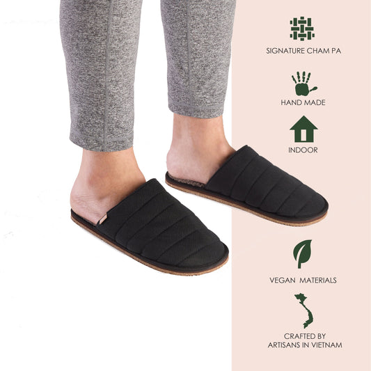 Pair of black slippers with quilted design on a white background