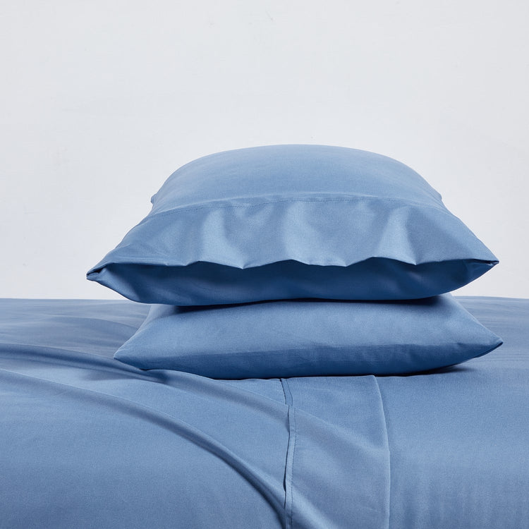 Blue bed sheets and pillows on a light gray background
