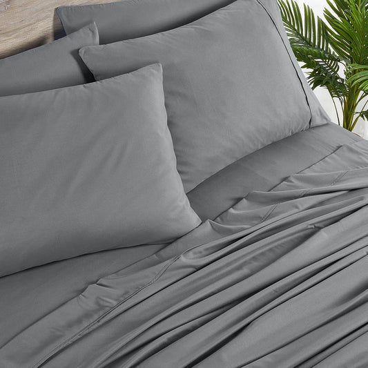 A charcoal grey 6 piece bamboo sheet set displayed on a bed, including a fitted sheet, a flat sheet, and pillow covers with a second pillow placed on the bed.