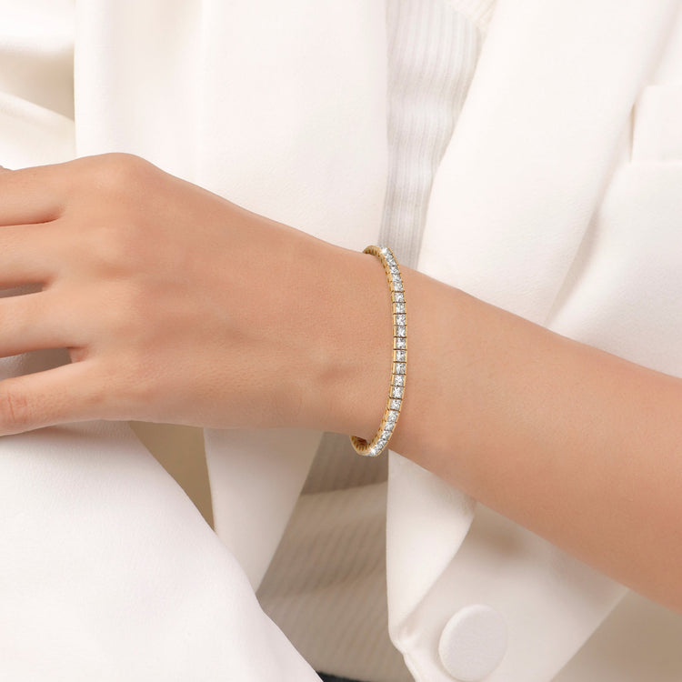 Gold bracelet on a person's wrist with a white background