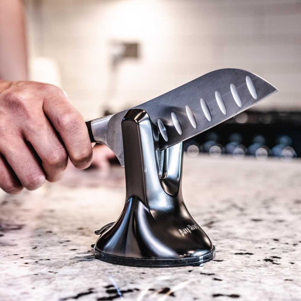 Person using a knife sharpener on a kitchen counter