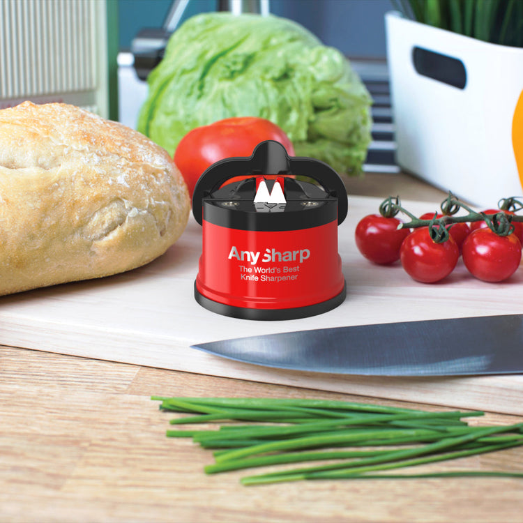 AnySharp knife sharpener on a kitchen counter with vegetables and bread in the background