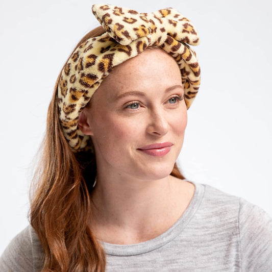 Woman wearing a leopard print headband against a plain background