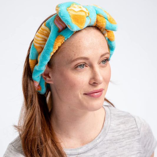 Woman wearing a colorful towel on her head against a white background
