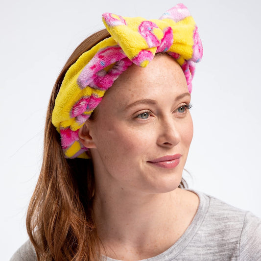 Woman wearing a colorful headband with pink and yellow hues on a white background