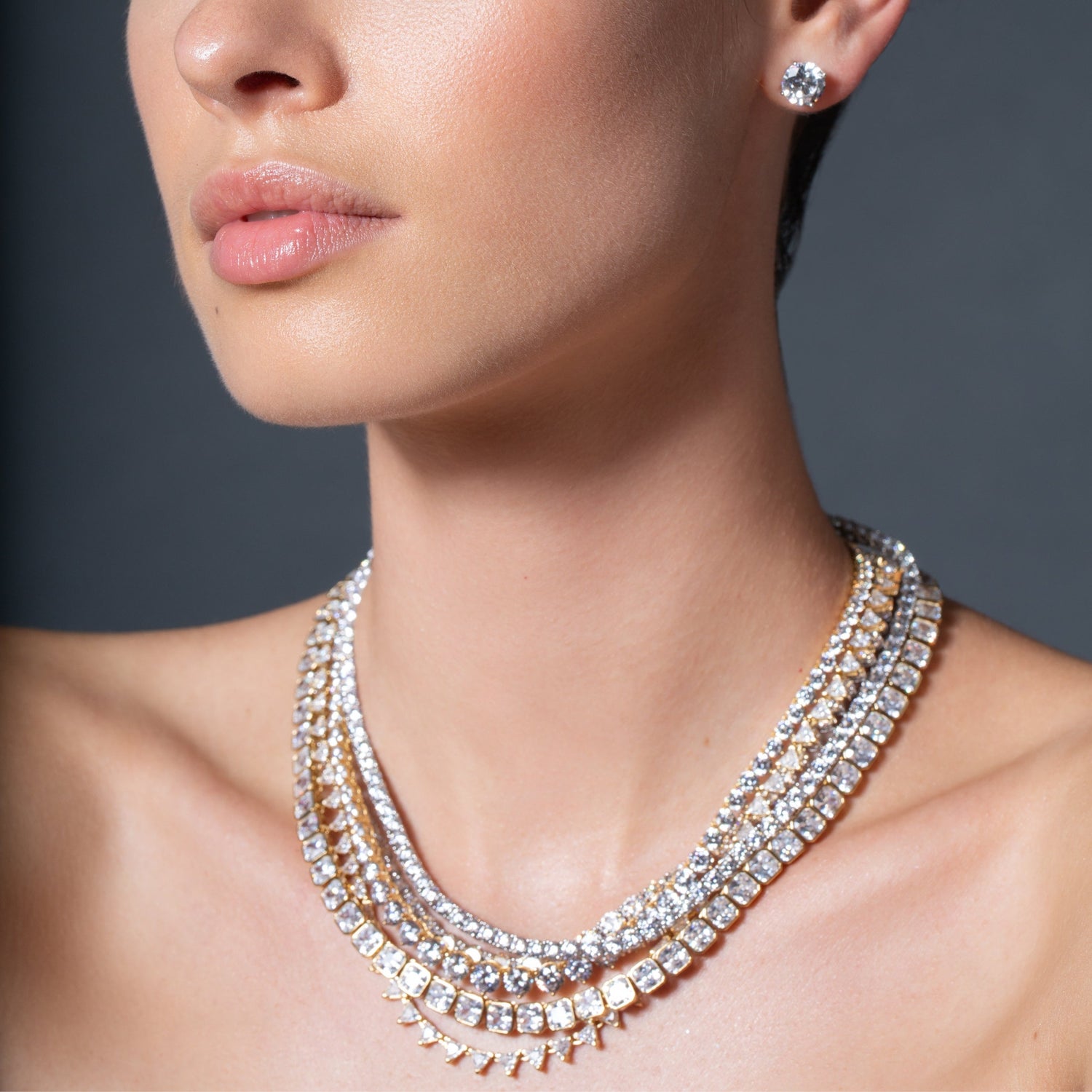 Close-up of a woman wearing a sparkling diamond necklace and earrings against a dark background