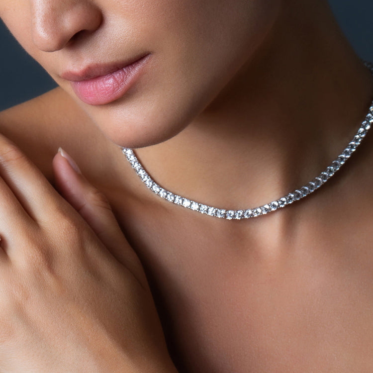 Close-up of a person wearing a silver necklace with a blurred background
