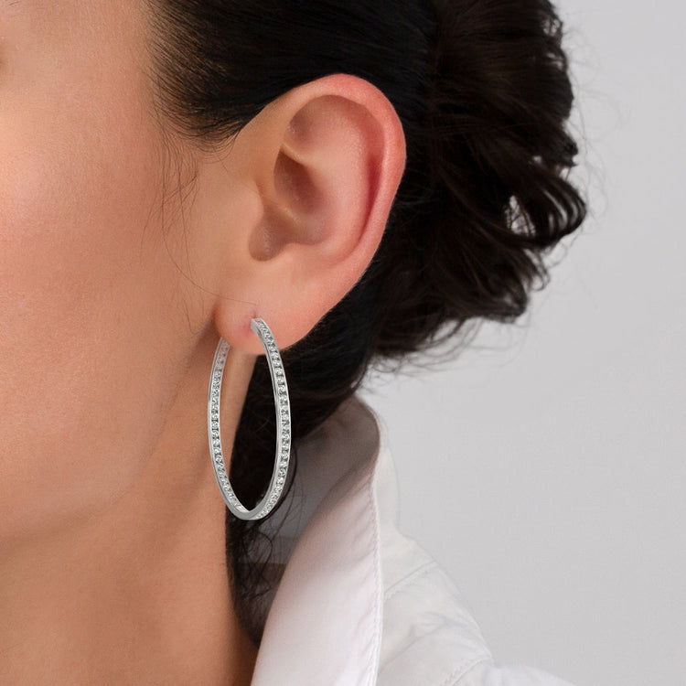 Silver hoop earring worn by a person with a neutral background