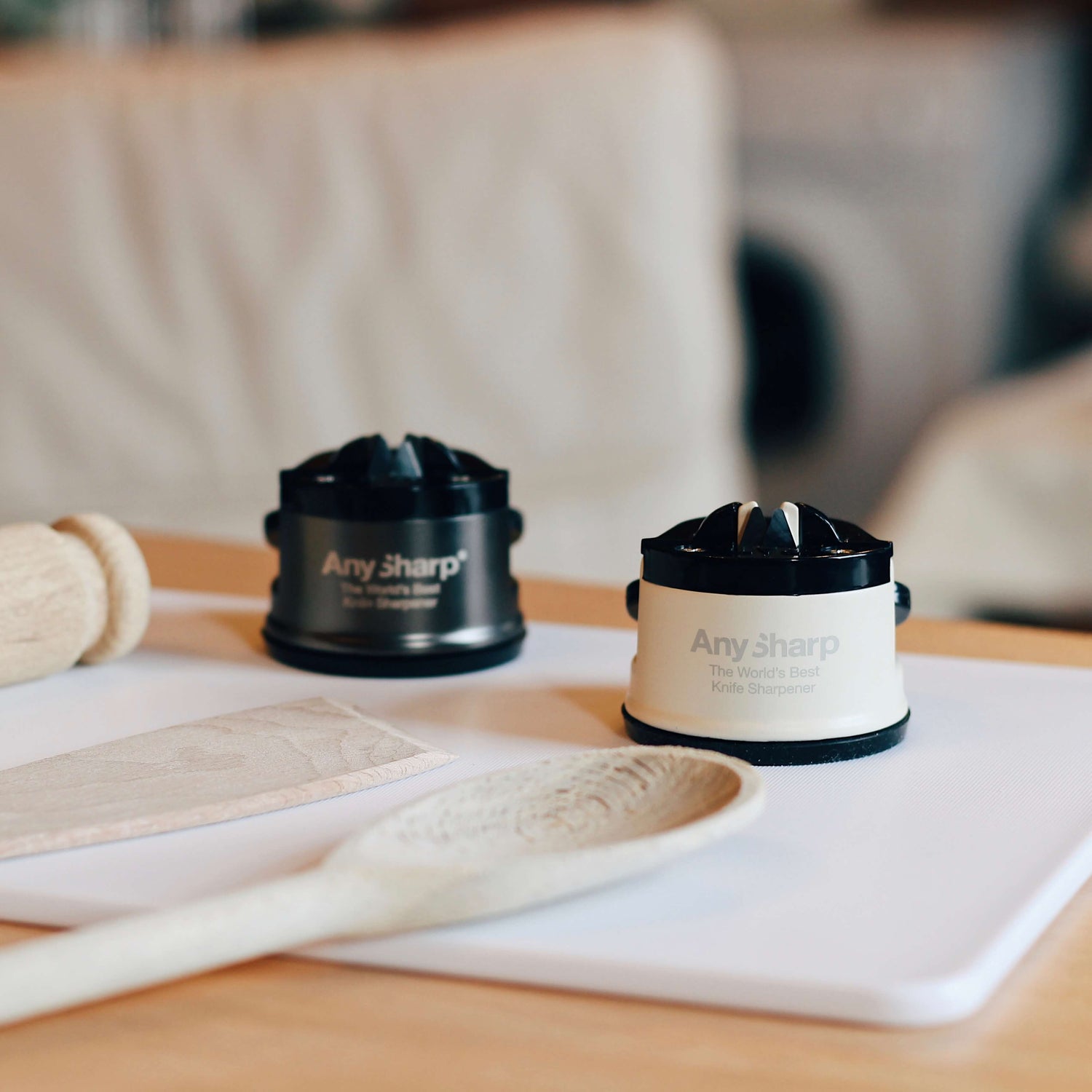 Two AnySharp knife sharpeners on a table with wooden spoons and a blurred background.