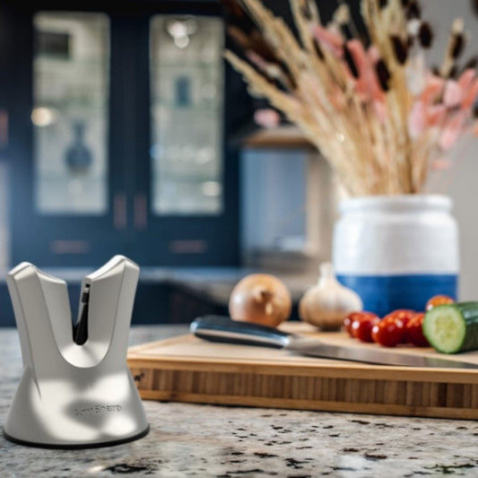 A black, professional knife sharpener with a suction cup base and a metallic blade.