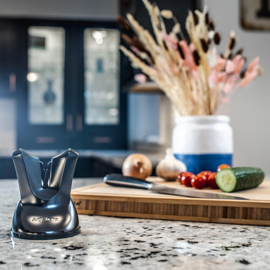 A black, professional knife sharpener with a suction cup base and a metallic blade.