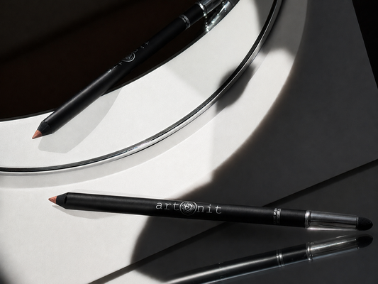 Black makeup pencils on a reflective surface with a mirror