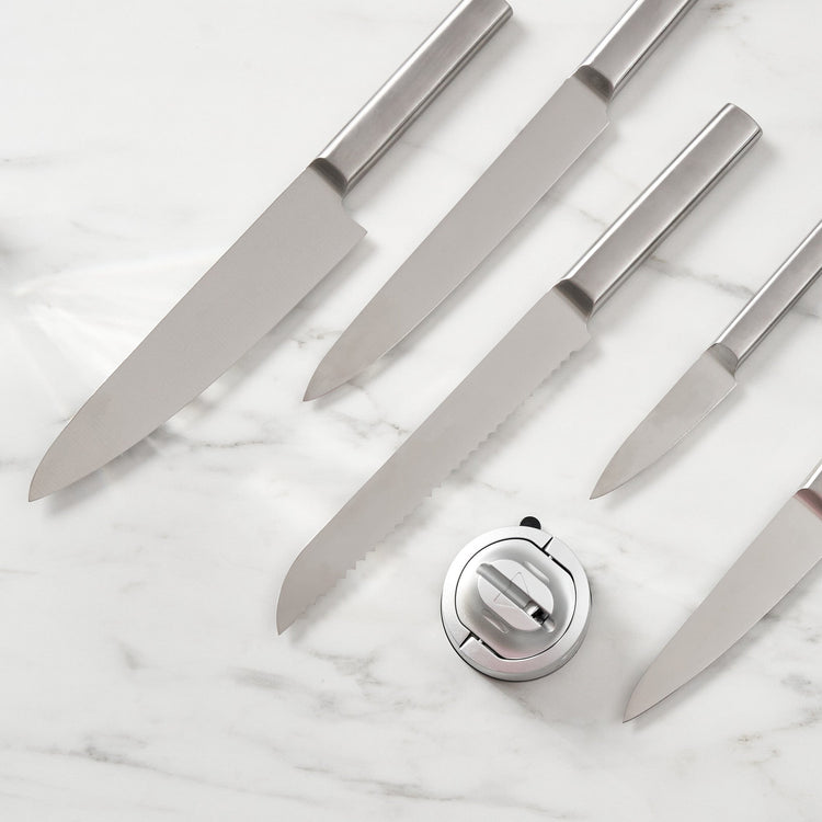 Set of knives on a marble surface with a knife sharpener.