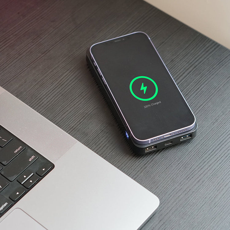 Phone with a charging icon on a desk next to a laptop