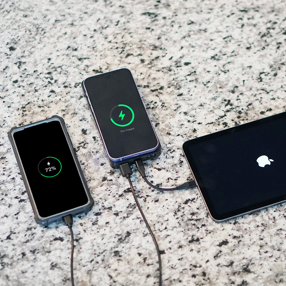 Three electronic devices charging on a granite surface