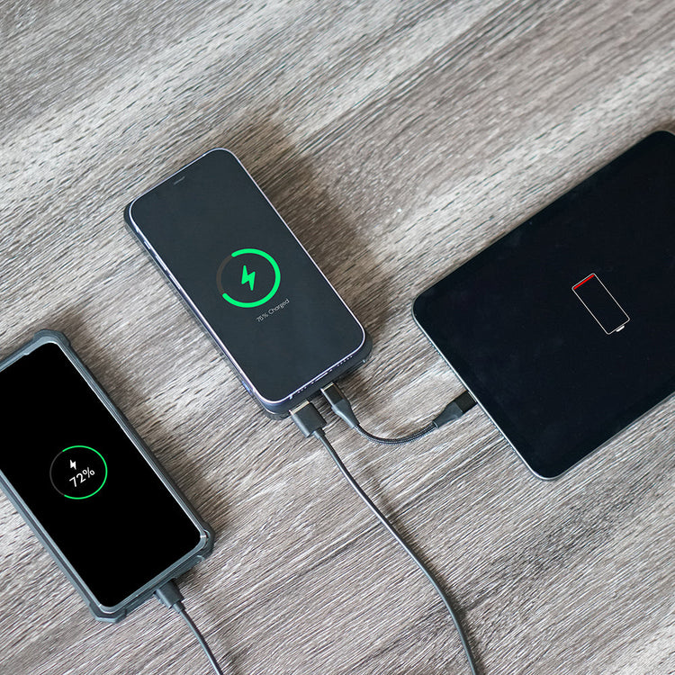 Two smartphones charging on a wooden surface with battery indicators displayed.