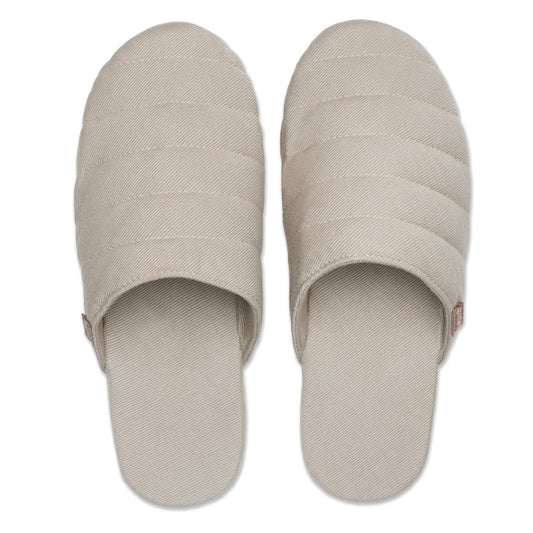 Pair of beige quilted slippers on a white background