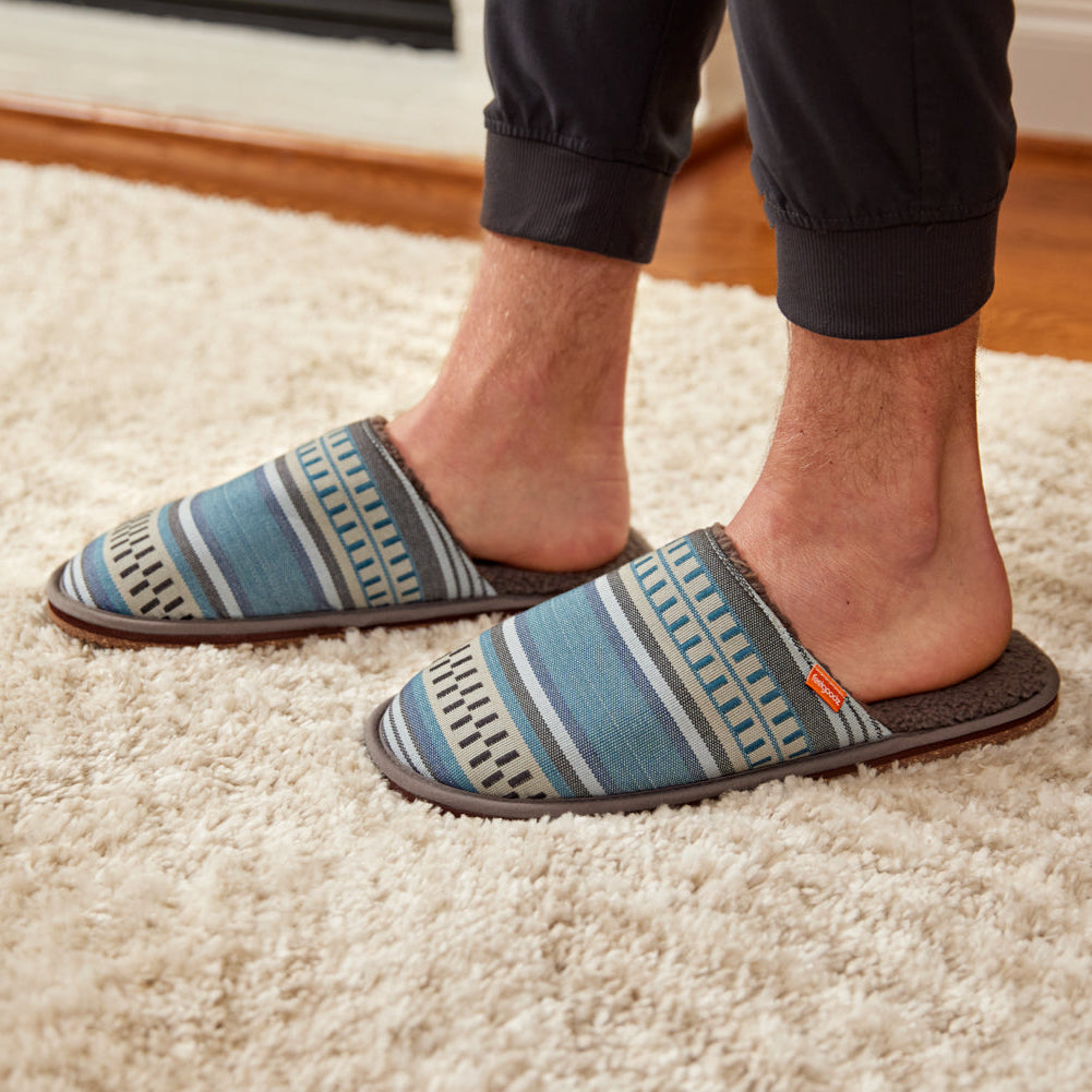 Person wearing patterned slippers on a carpeted floor
