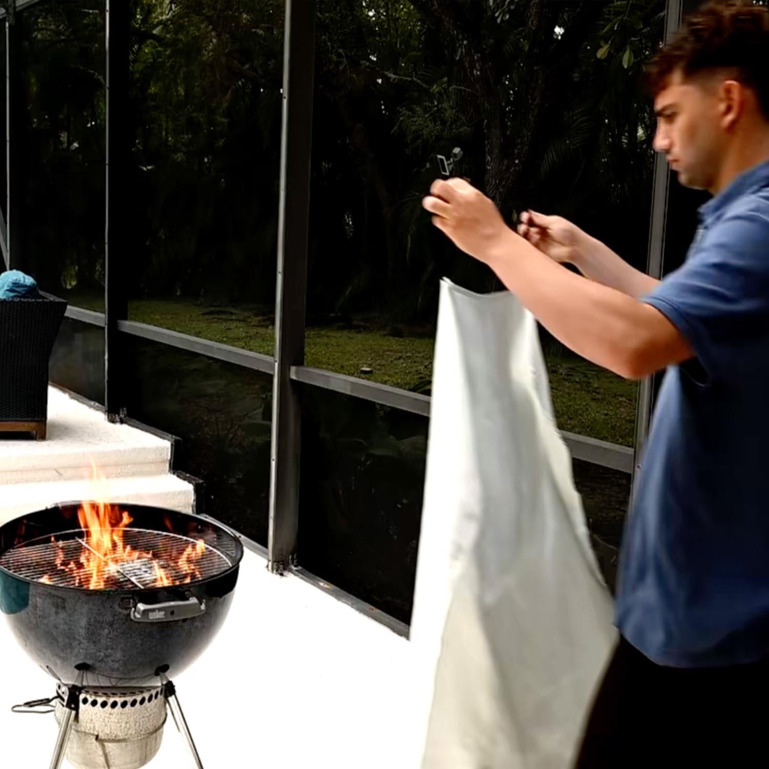 Person using a smartphone near a grill with flames outdoors