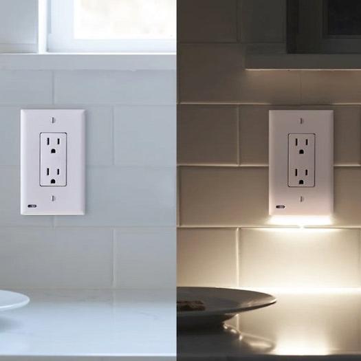 A white 2-pack of GuideLight outlet cover plates with built-in LED lights, mounted on a blue wall with the outlets visible at the bottom.
