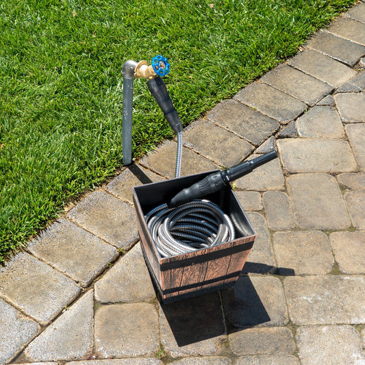 Metal garden hose with various nozzles in a wooden box on a white background
