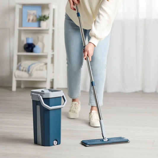 Person cleaning a floor with a mop and bucket in a room.