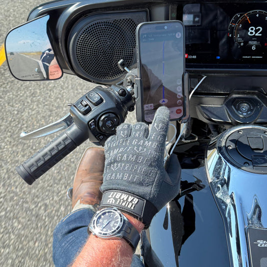 Man wearing ear protection, sunglasses, and gloves outdoors with a clear sky.