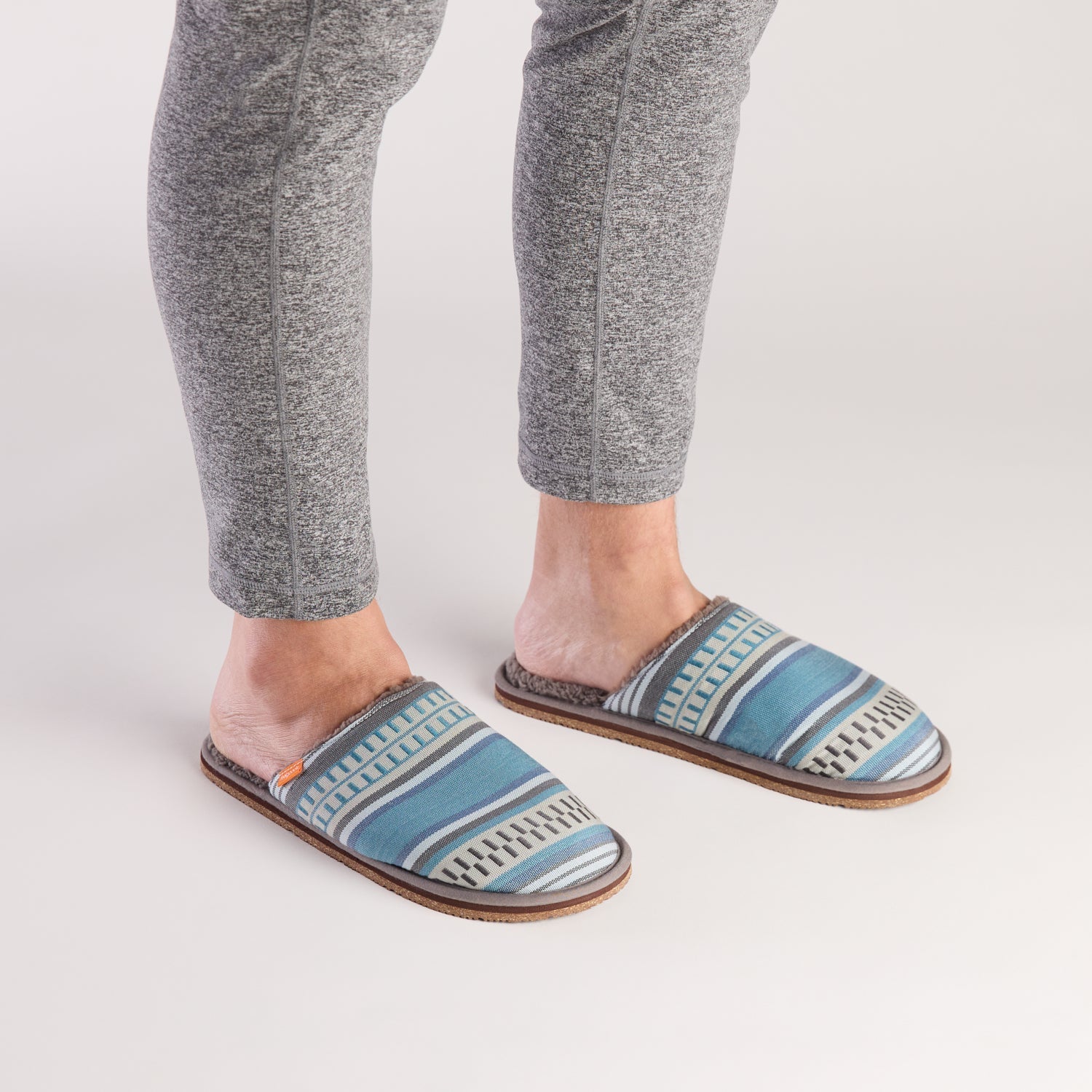 Person wearing blue patterned slippers on a white background